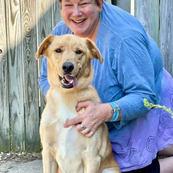 A woman and her dog are smiling for the camera.